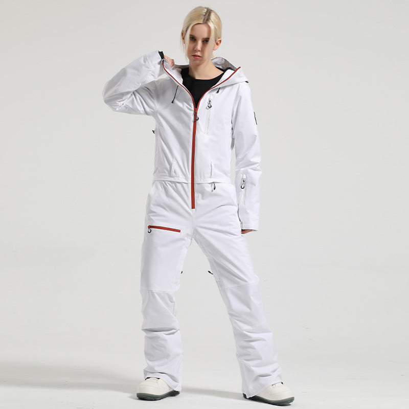 Front view of a model wearing the white Alpine Access one-piece ski suit with contrasting orange zipper trim.