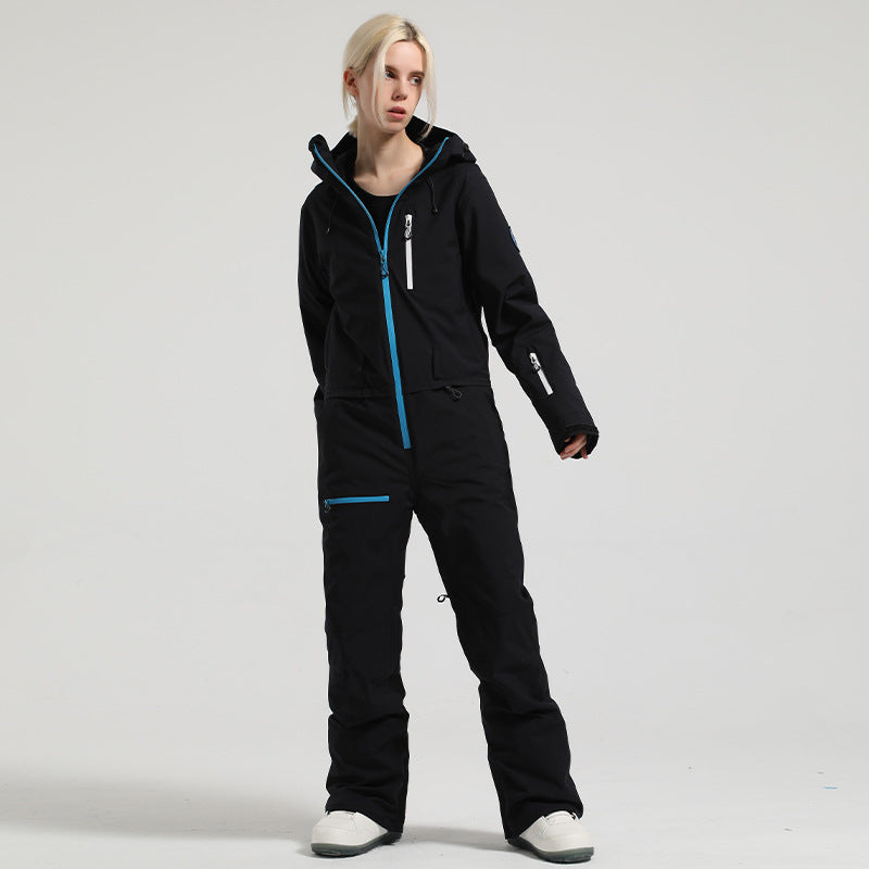 Model wearing the black Alpine Access one-piece ski suit with blue zipper trim and a sleeve pocket.